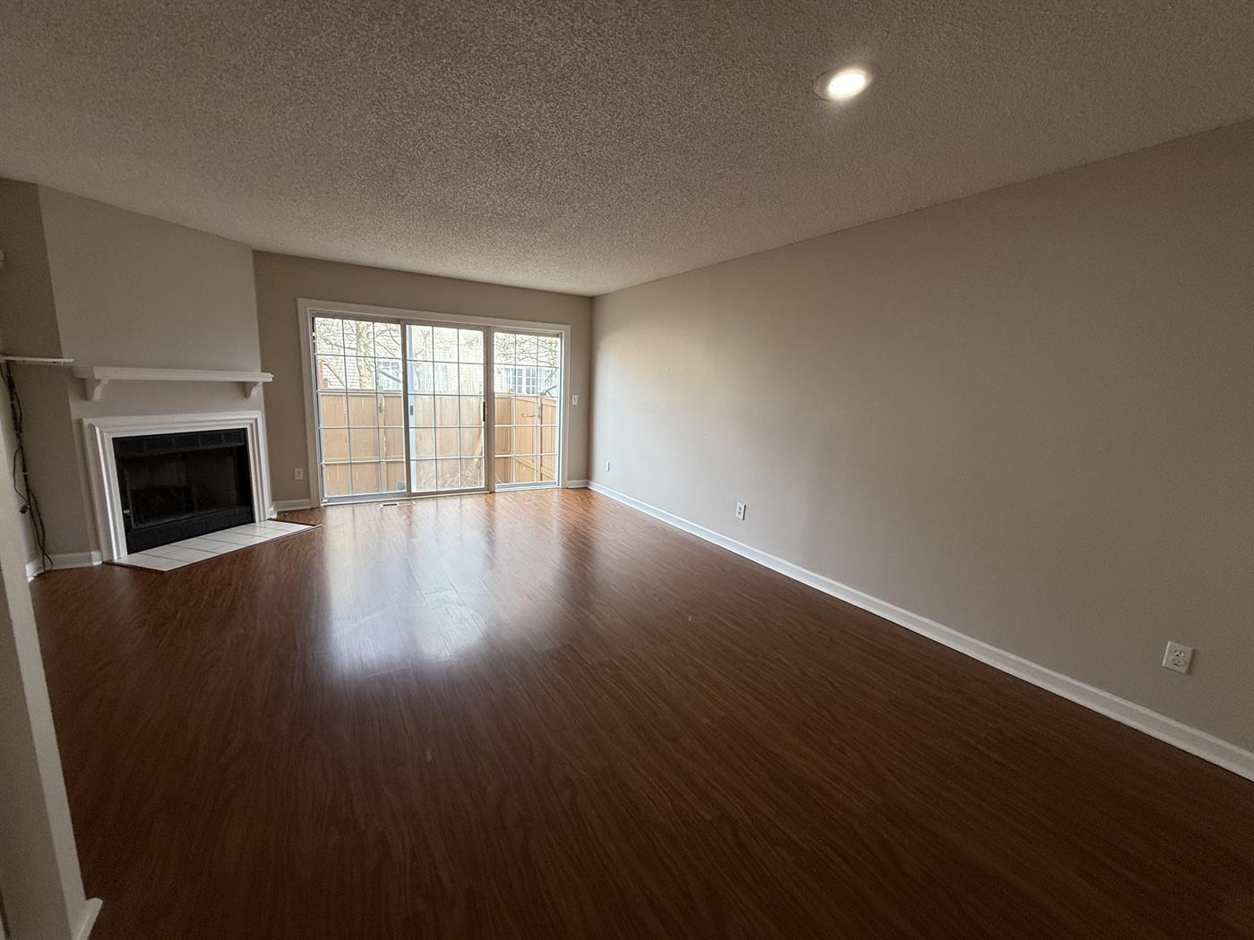 Bright living room in a Hilliard condo featuring a decorative fireplace, neutral carpeting, and large windows with natural light.
